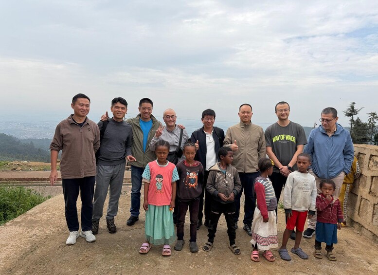 A group of people standing on a concrete ledge with a mountainous landscape in the background. 4