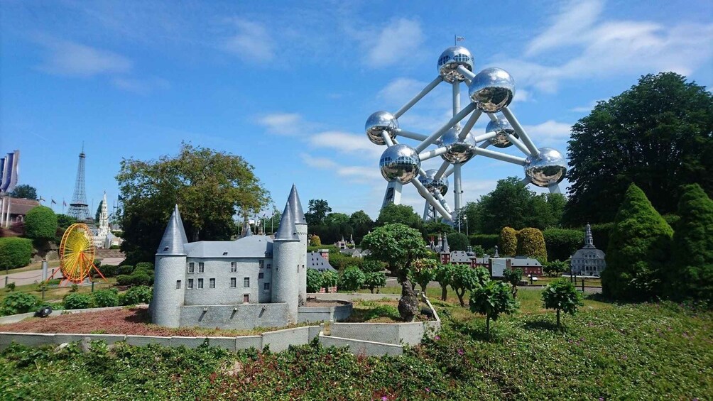 A castle, a Ferris wheel, and a large metallic sculpture in a park. 2
