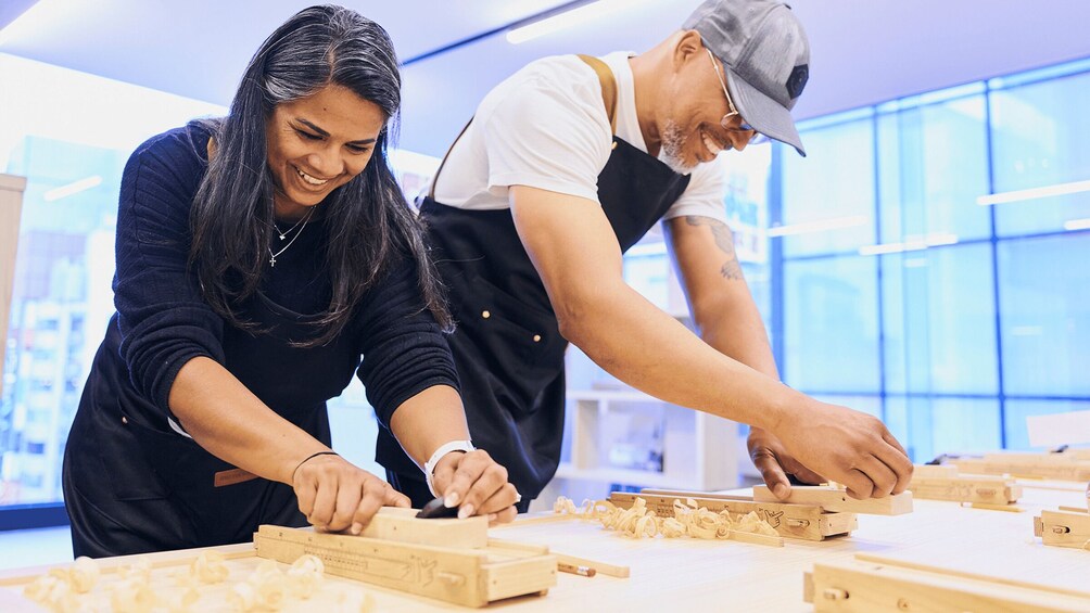 Two people working on wooden blocks in a workshop. 4