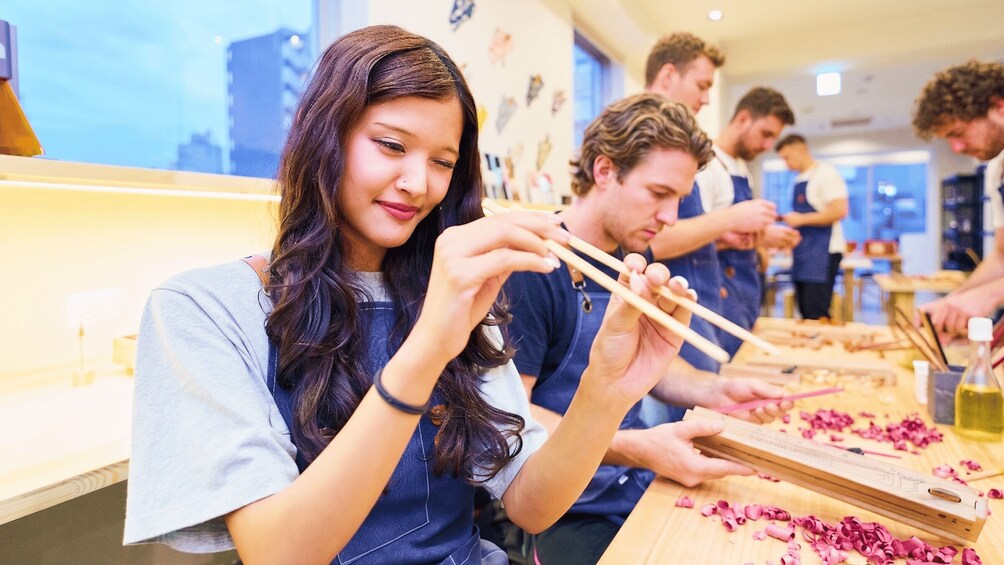 People engaged in a cooking class, using chopsticks to handle food on wooden cutting boards. 3