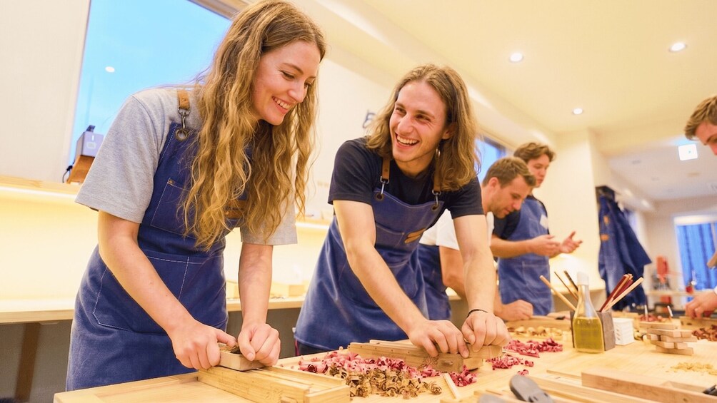 People engaged in a cooking activity, wearing aprons, with wooden cutting boards and ingredients on the table. 2
