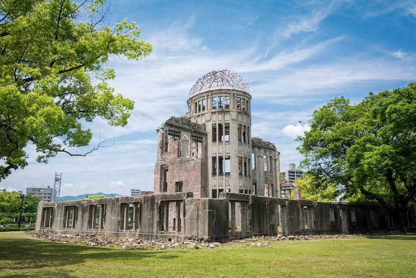 An abandoned building with a dome and columns, surrounded by trees and grass. 2