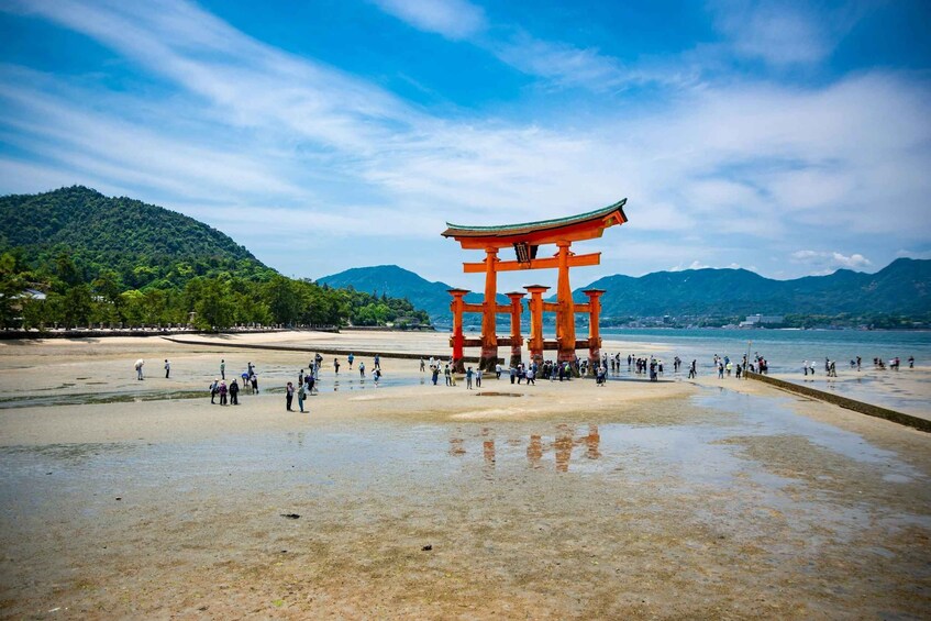 A traditional Japanese torii gate at a beach with people walking around it. 5