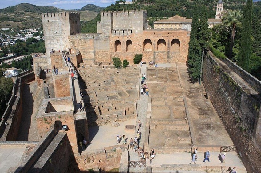 A historical fortress with a large courtyard, stone walls, and arched gateways. 2