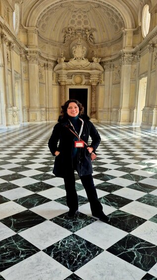 A person standing in a grand hall with a checkered marble floor and ornate ceiling. 2