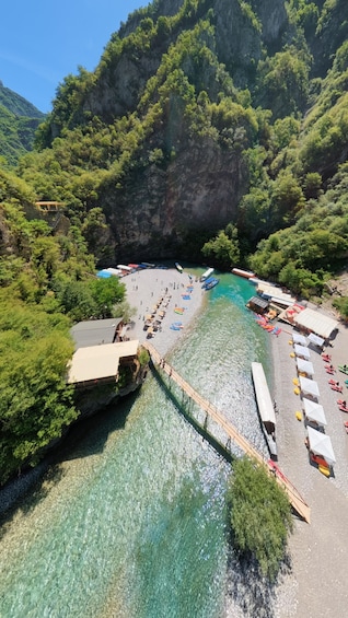 A coastal beach with clear turquoise water, a wooden pier, and a row of boats. 1