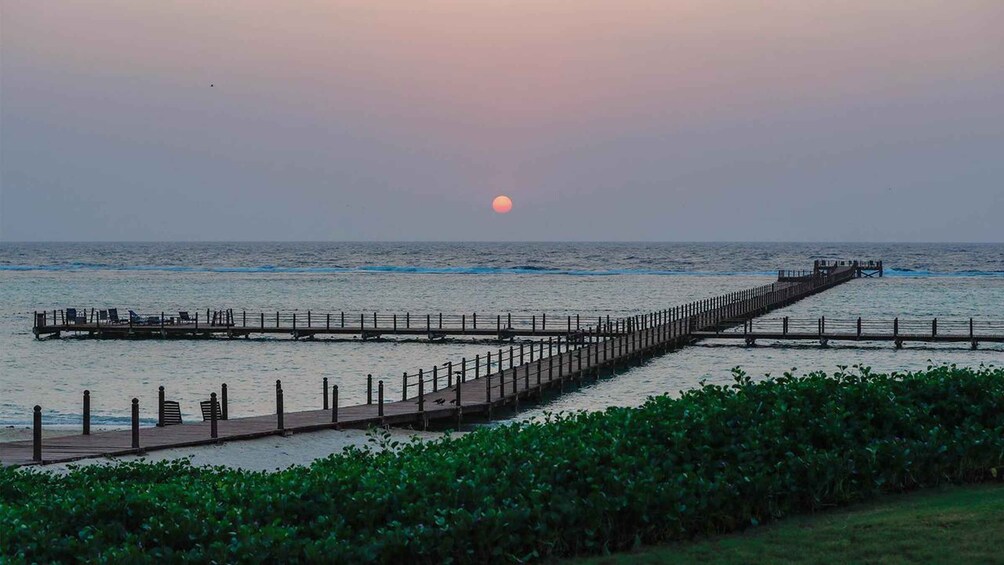 A pier extending into the ocean at sunset. 1