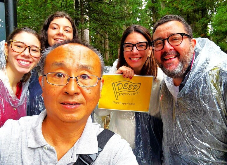 A group of people outdoors, some wearing raincoats, holding a sign that reads "Deep Experience." 1