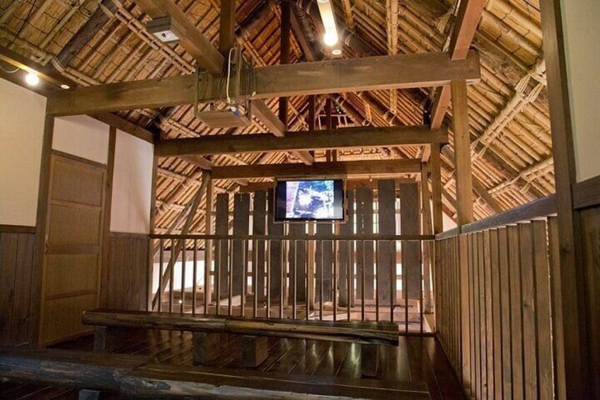 Une structure rustique en bois, dotée d’un toit de chaume, d’un banc en bois et d’un écran de télévision. 2