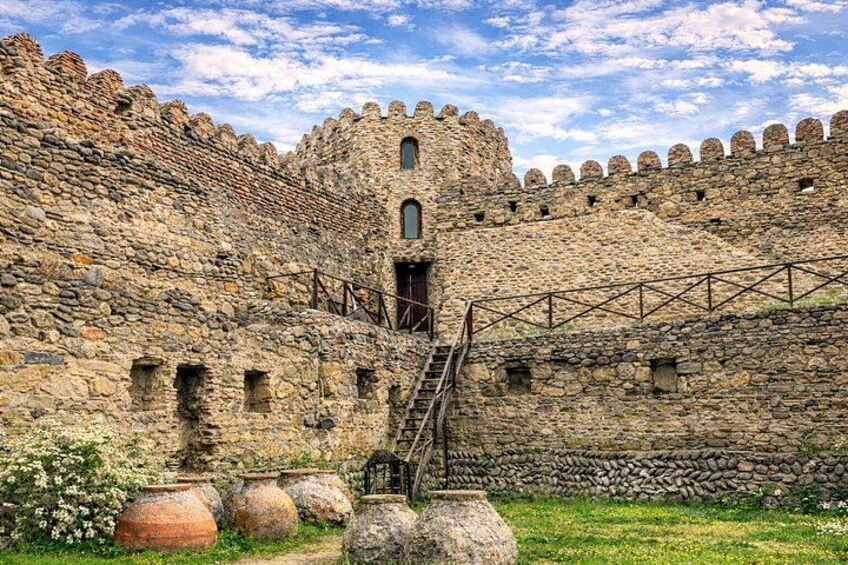 A stone castle with a central tower, a wooden staircase, and a surrounding wall. 2