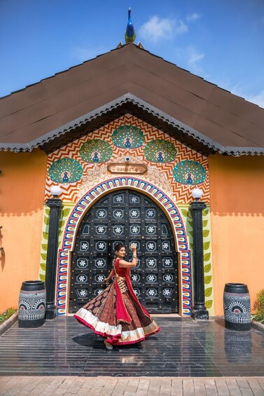 A woman in traditional attire standing in front of a colorful, ornately decorated building with a large black door. 2