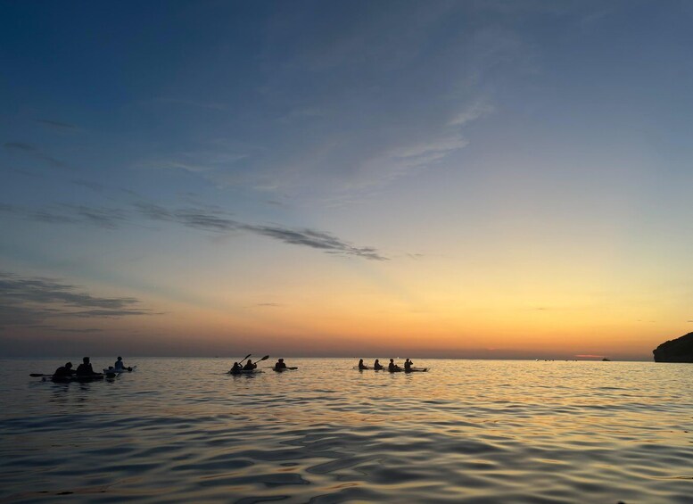 A sunset over calm water with kayakers. 3