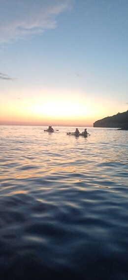 A calm sea at sunset with three boats in the distance. 5