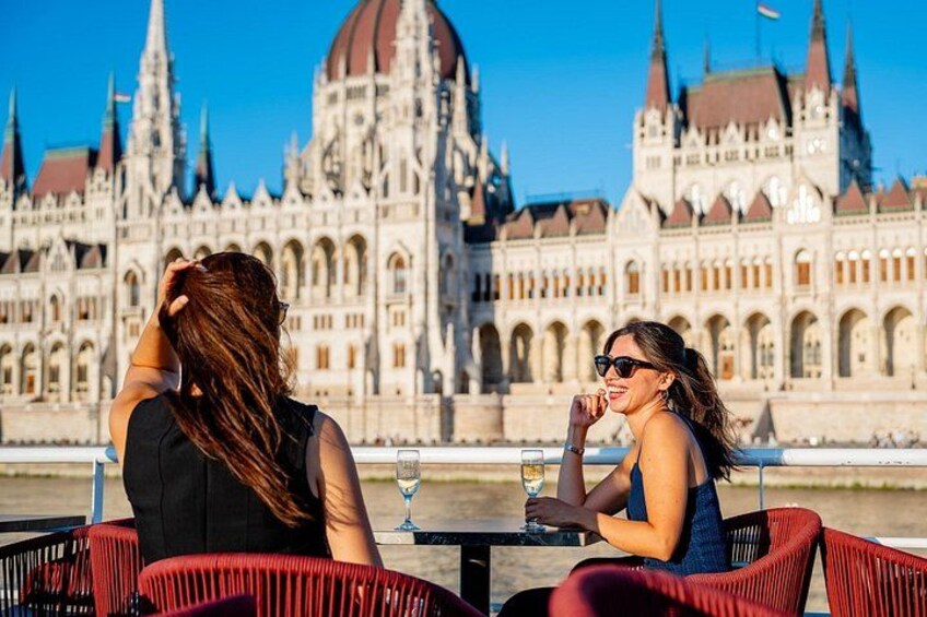 Two people sitting at a table with a view of a historic building with multiple spires. 1