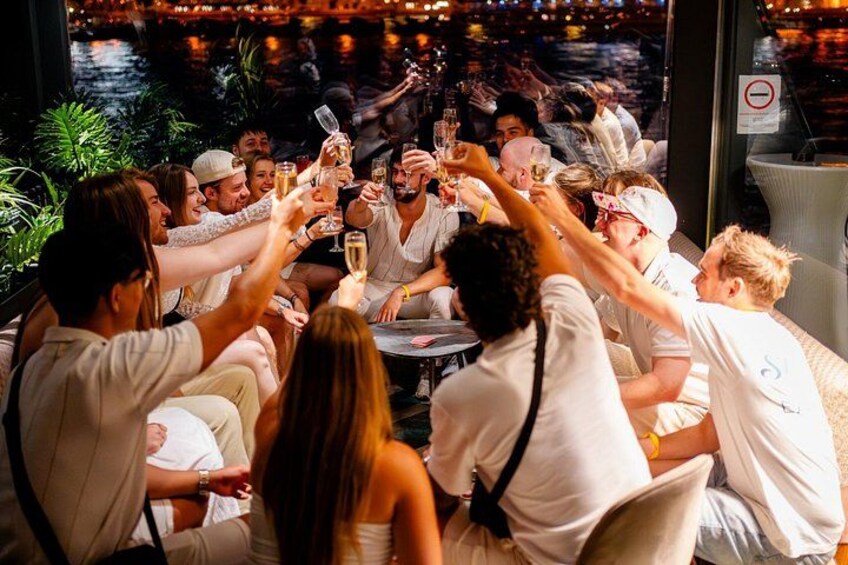 Een groep mensen proost met champagneglazen aan een tafel. 2