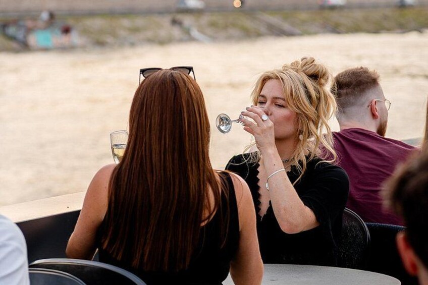 Een café aan het strand met mensen die aan tafels zitten en van hun drankjes genieten. 4