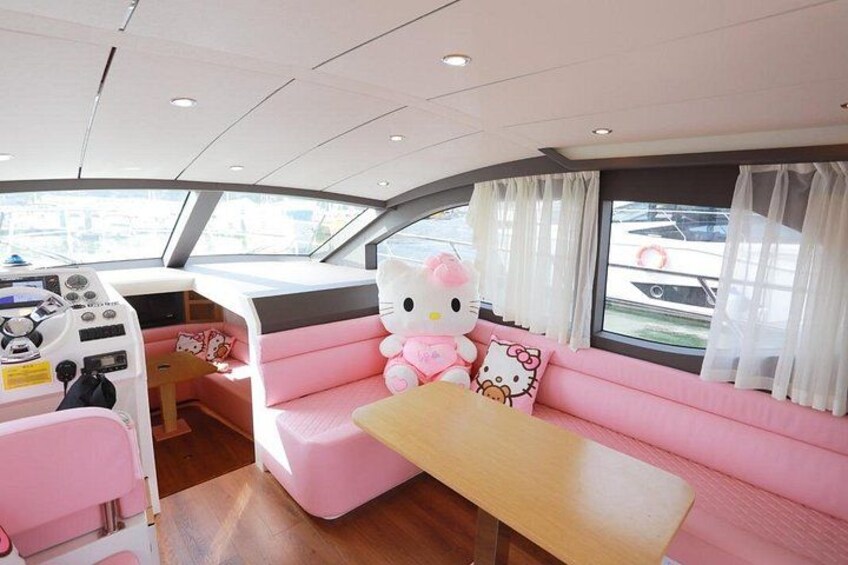 Interior de un bote con asientos rosados, un peluche grande de Hello Kitty y un volante. 5