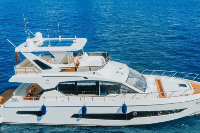 Un yate blanco con cabina y asientos en la cubierta, navegando sobre aguas azules. 1