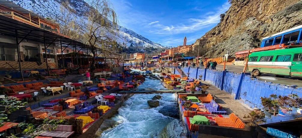 A riverside market with stalls and a bus on the road. 1