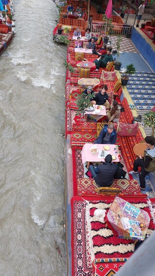 A riverside dining area with colorful carpets and tables. 4