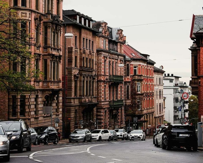 A street lined with historic brick buildings, parked cars, and a speed limit sign. 3