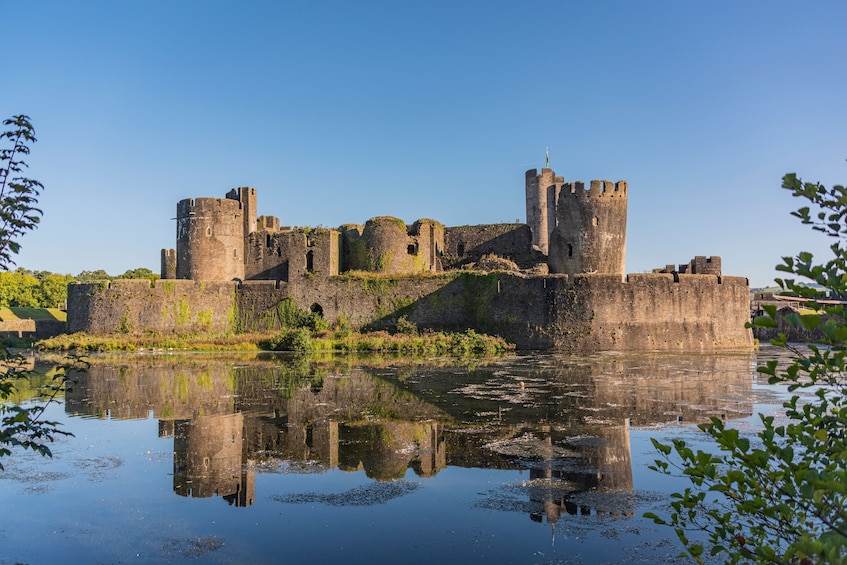 A historic castle surrounded by water with reflections. 4