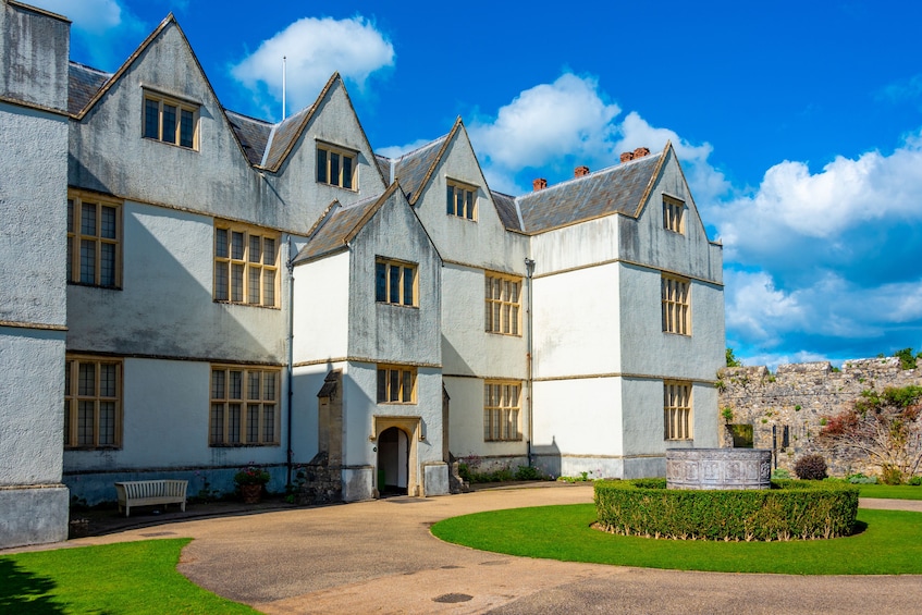 A large, historic building with multiple gabled roofs and a well-maintained lawn. 3