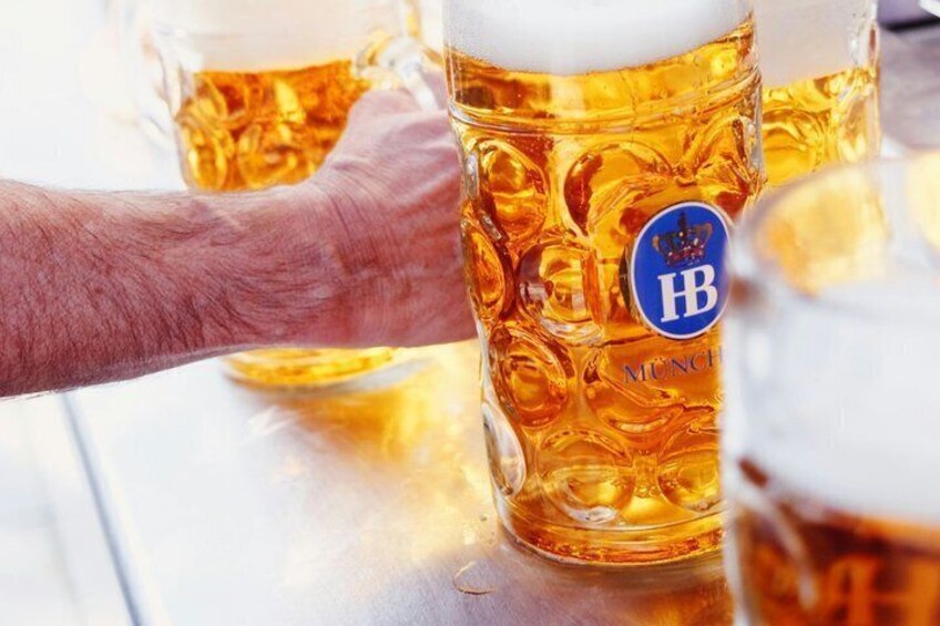 En hånd holder et stort ølglas med en logo. 3