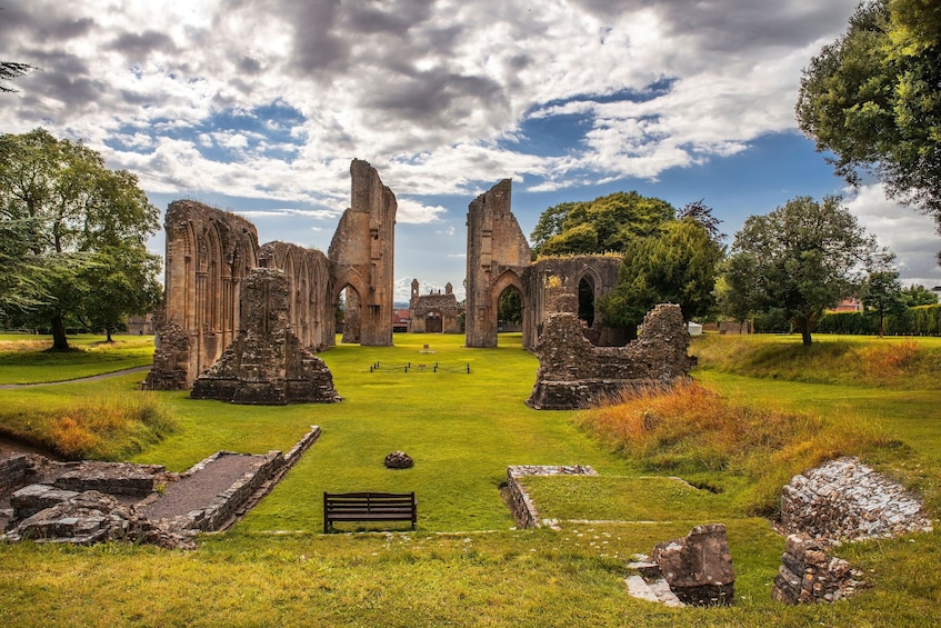 Ancient ruins with stone arches and columns, surrounded by grass and trees. 3