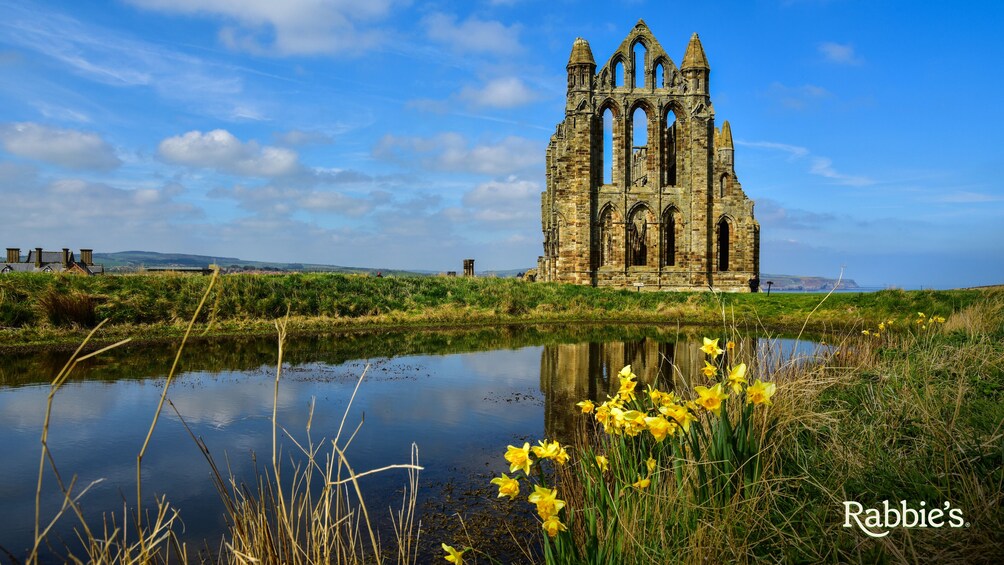 A historic stone church with a large body of water in the foreground and a clear blue sky. 5