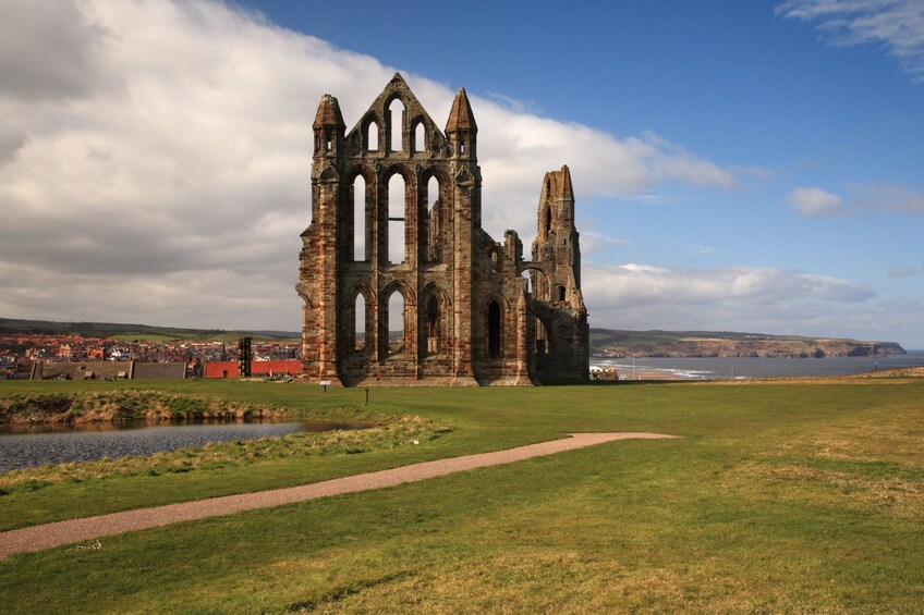 A historic stone cathedral with tall arches and a river in the foreground. 2