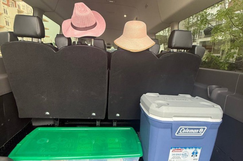 A vehicle's back seat with two hats and a Coleman cooler. 4