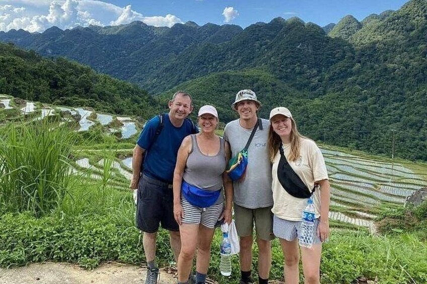 A group of people standing in a rice paddy field with terraced hills in the background. 3