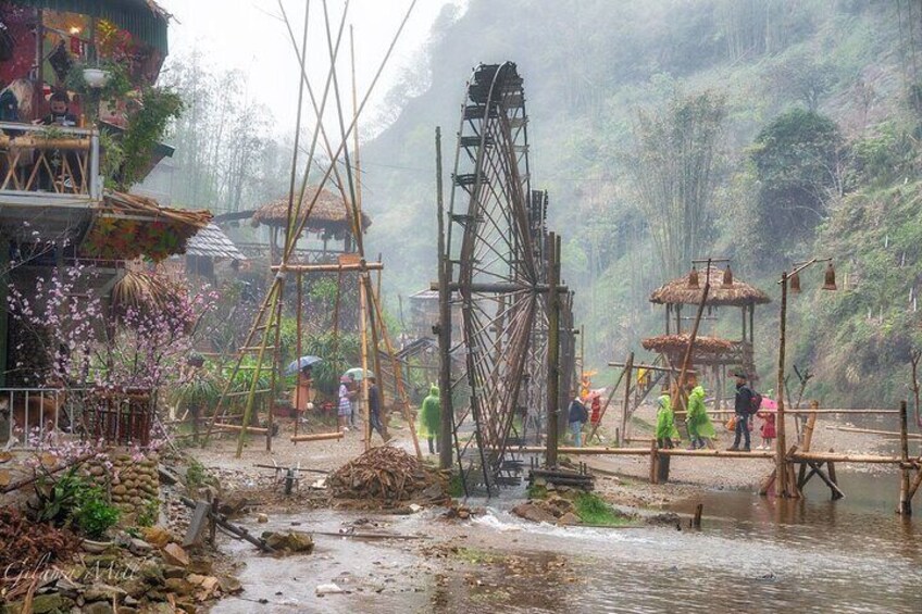 A traditional water wheel, wooden structures, and a river in a forested area. 4