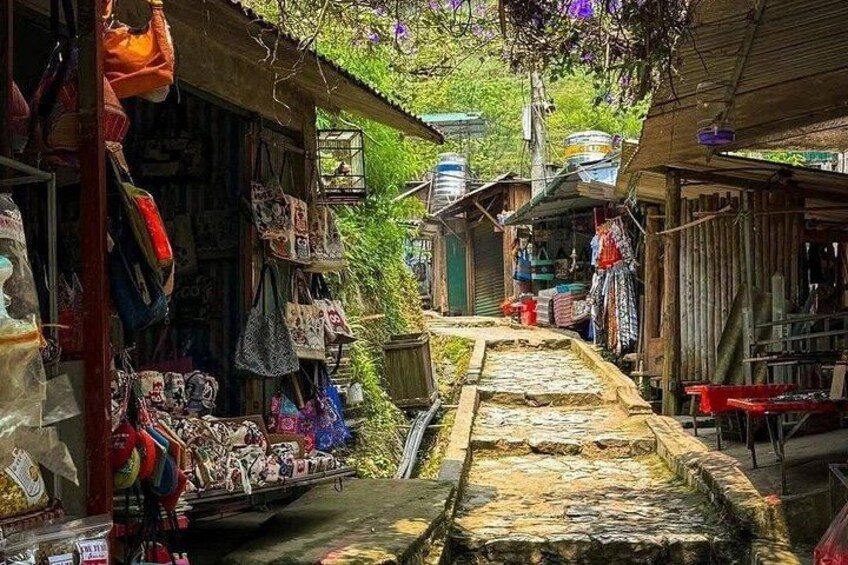 A narrow alley with shops on either side, wooden structures, and a stone pathway. 1