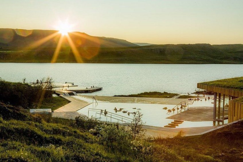 Un complejo turístico frente a un lago con muelle de madera, un pequeño embarcadero y una zona verde. 2