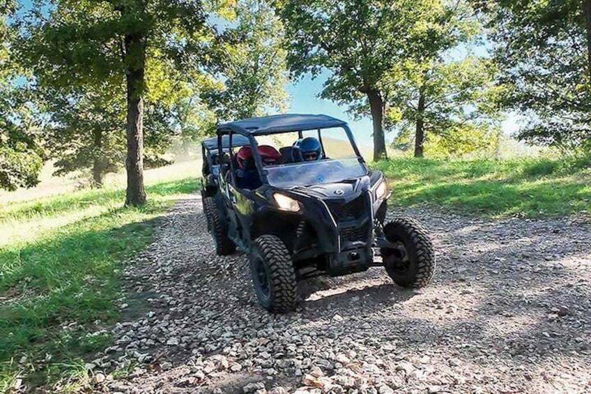 A black off-road vehicle on a gravel path surrounded by trees. 2