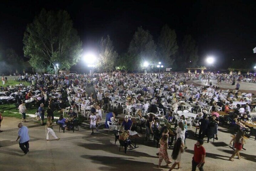A large outdoor gathering at night with people seated at tables under bright lights. 3