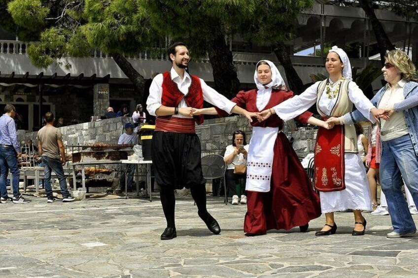 People in traditional costumes dancing in a public square. 1