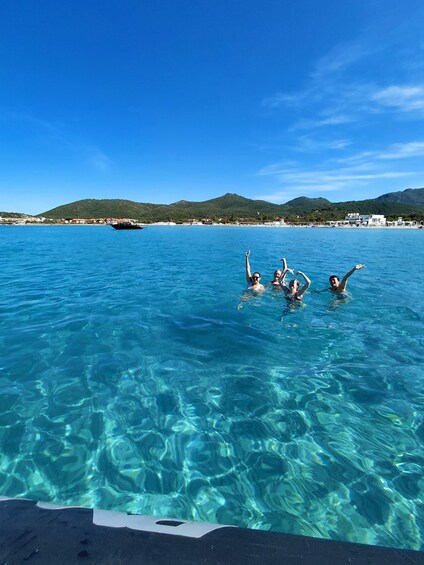 A group of people swimming in clear blue water with a mountainous landscape in the background. 1