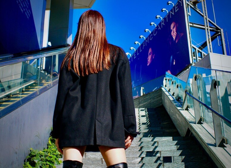 A person walking down a staircase with glass railings and a blue sky in the background. 1