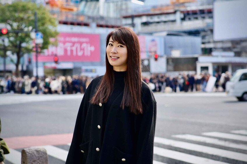 A person standing on a crosswalk in a busy urban area with buildings and billboards in the background. 5