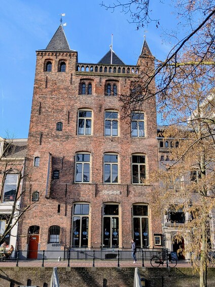 A historic brick building with a tower, arched windows, and a red door. 3