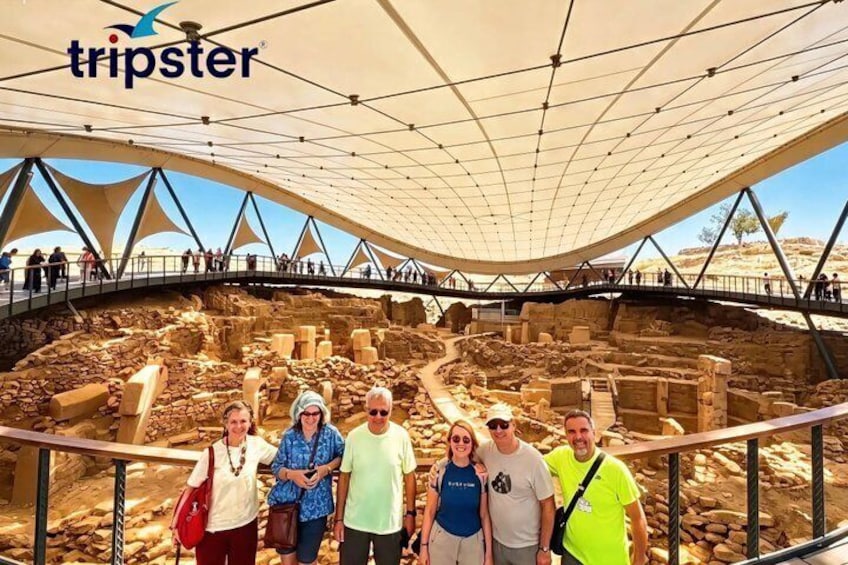 A group of people at an archaeological site with a large open-air structure overhead. 3