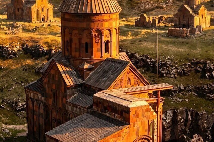 A historic church with a bell tower, surrounded by ruins and a grassy landscape. 2