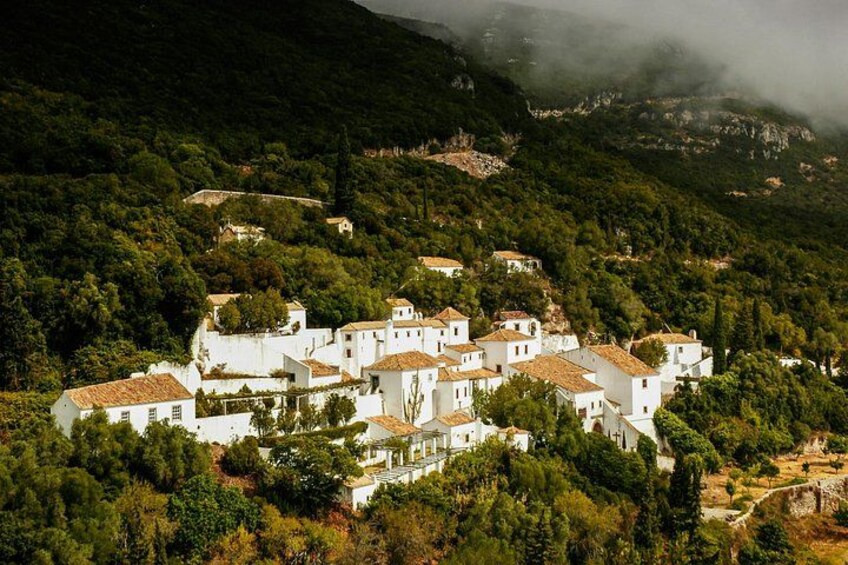 Un village blanc niché dans une région montagneuse, entouré d’une végétation luxuriante. 4