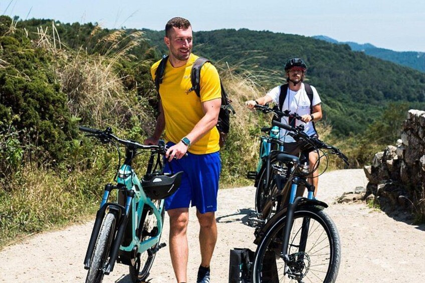To cyklister på en grussti med et bjergrigt landskab i baggrunden. 2