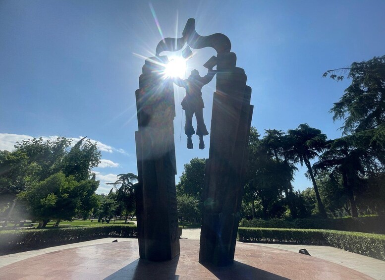 A sculpture of two figures holding hands with a bright light source behind them. 2