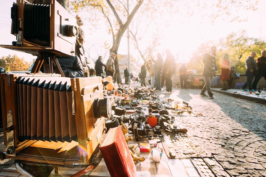 A vintage camera on a tripod with various camera parts and accessories scattered on the ground. 5
