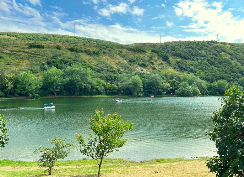 A lake with boats, surrounded by lush green hills and trees. 1